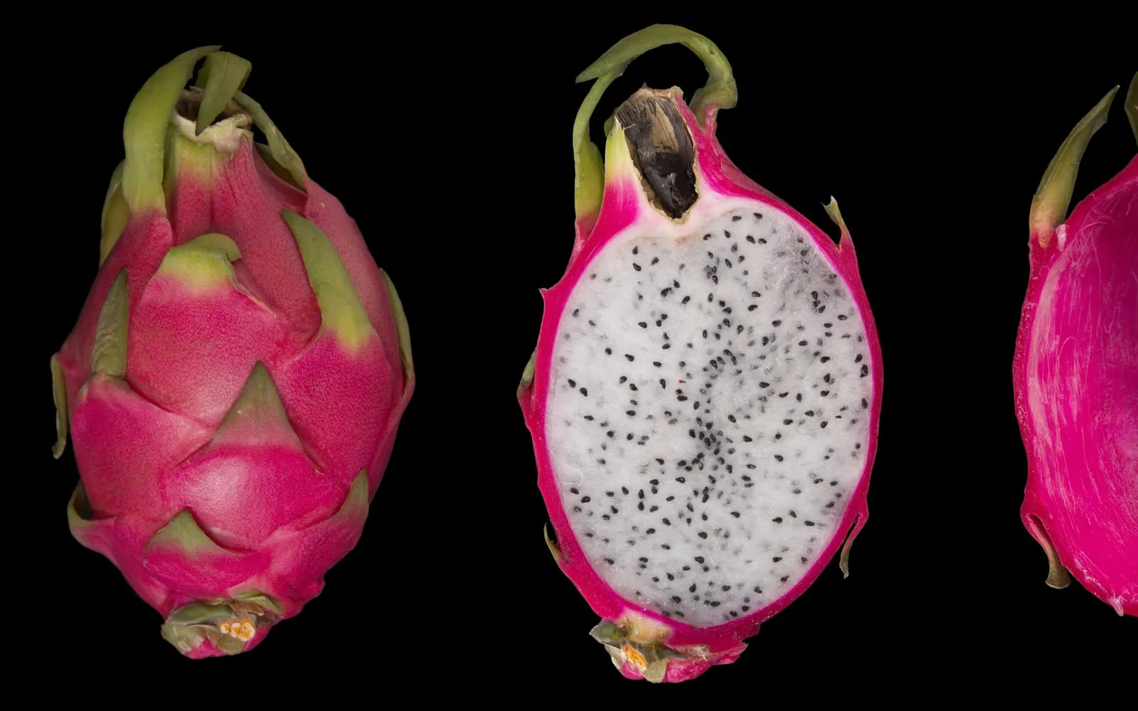 Whole and halved dragon fruit, showing the pink, leaf-bracted skin and white seed-studded flesh